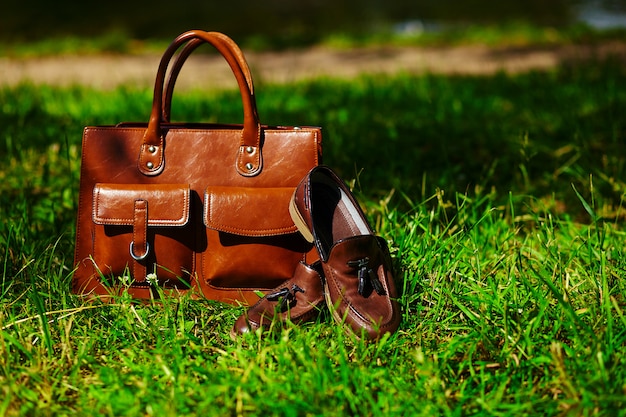 Retro brown shoes and man leather bag in bright colorful summer grass in the park