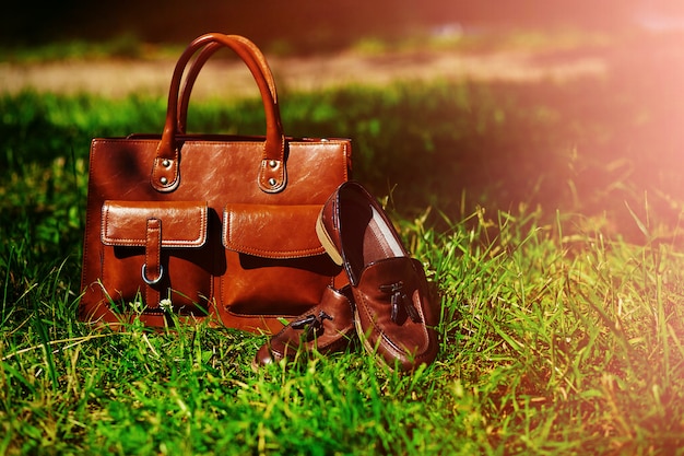 Ретро коричневые туфли и мужская кожаная сумка в яркой красочной летней траве в парке