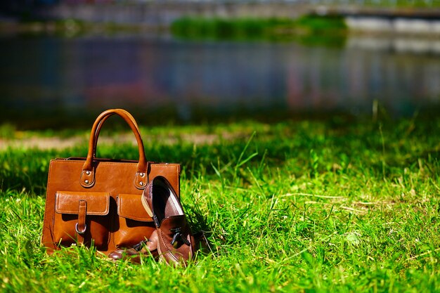 Ретро коричневые туфли и мужская кожаная сумка в яркой красочной летней траве в парке