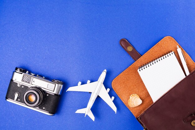 Retro camera near toy plane and case with notepad