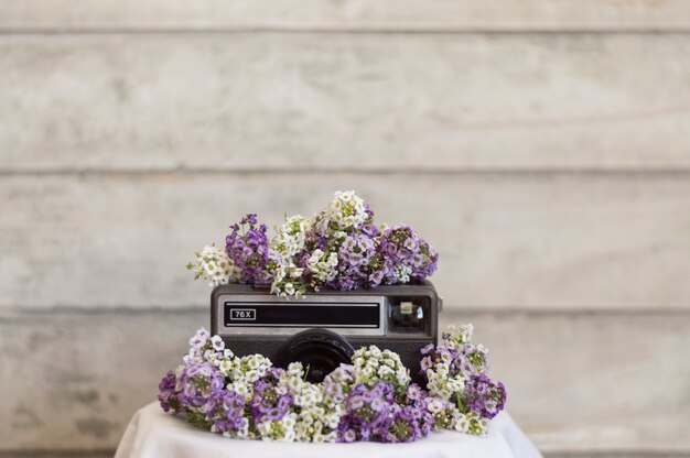 보라색과 흰색 꽃으로 둘러싸인 레트로 카메라