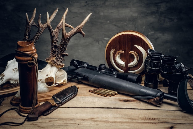 ライフルと双眼鏡のレトロな狩猟用弾薬。木製のテーブルに美味しいソーセージと茶色のパン。