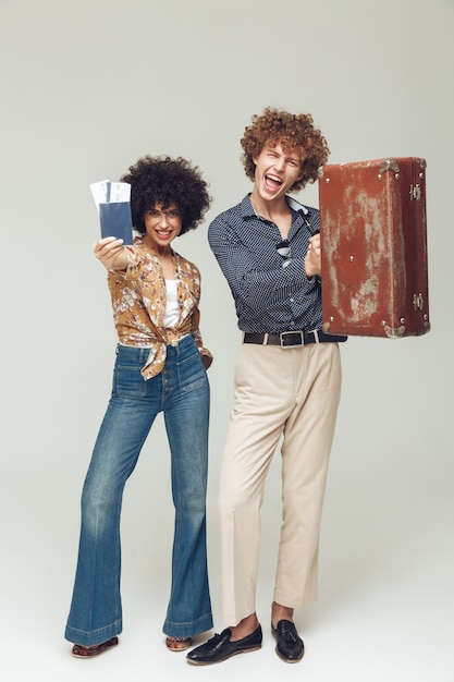 Free photo retro loving couple holding suitcase passport and tickets.