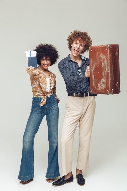 Retro loving couple holding suitcase passport and tickets.