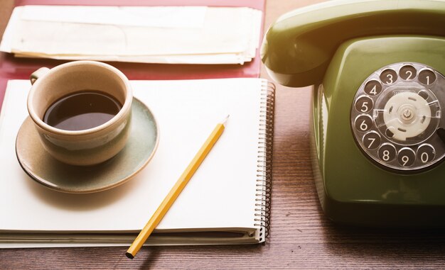 レトロな電話、ノートブック、コーヒーカップ
