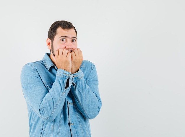 Free photo retro-style man covering his mouth with fists in jacket,t-shirt and looking frightened. front view. free space for your text