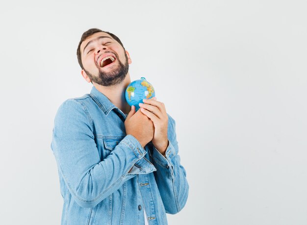 Free photo retro-style man hugging mini globe in jacket,t-shirt and looking merry. front view. space for text