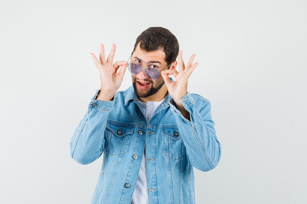 Retro-style man in jacket,t-shirt wearing sunglasses and looking jolly , front view.