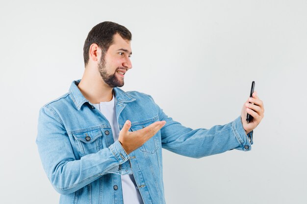 Retro-style man making video call in jacket,t-shirt and looking focused. .