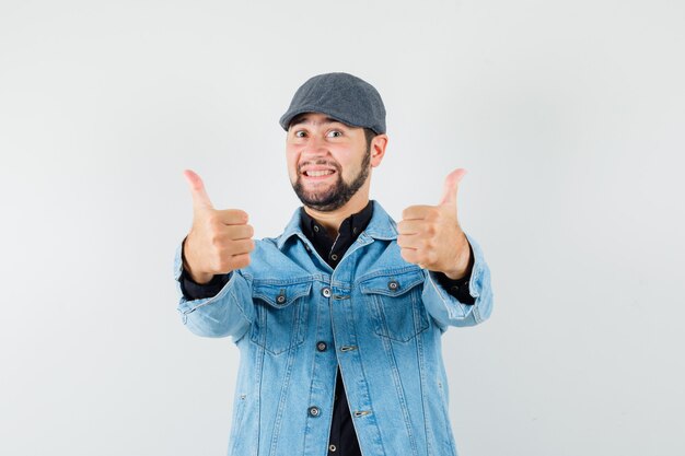 Retro-style man showing thumb up in jacket,cap and looking satisfied , front view.