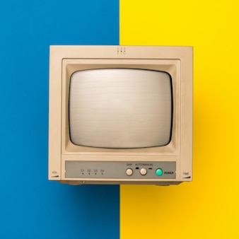 黄色​と​青​の​表面​に​レ​トロ​な​テレビ​。​上​から​の​眺め​。​ヴィンテージ​の​電子​機器​。