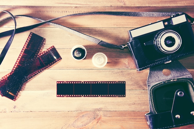 Retro vintage camera and photographic film on wooden background