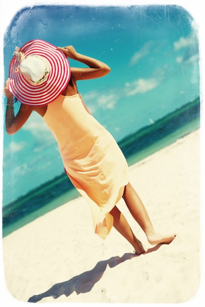 ретро старинные фото горячей красивой женщины в красочной шляпе от солнца и платье, прогулки возле пляжа океана в жаркий летний день на белом песке