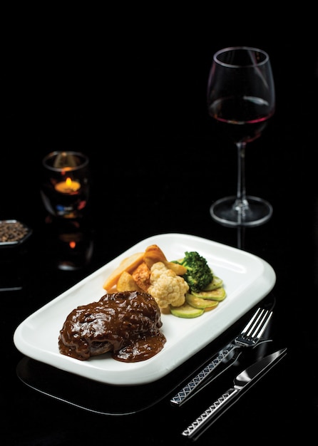 Free photo ribeye steak in teriyaki sauce with glass of burgundy