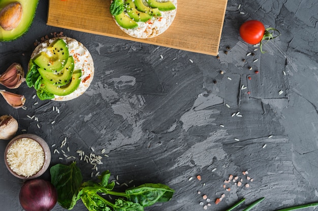 Rice cake with cream cheese; avocado and fresh ingredients over cement texture