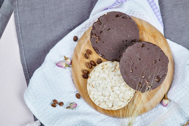 Rice and chocolate crackers on a wooden plate with a tablecloth.