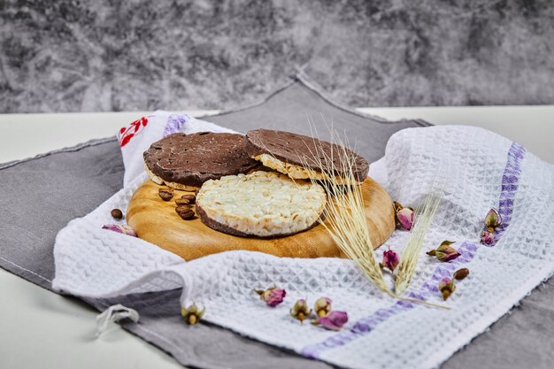 Rice and chocolate crackers on a wooden plate with a tablecloth.