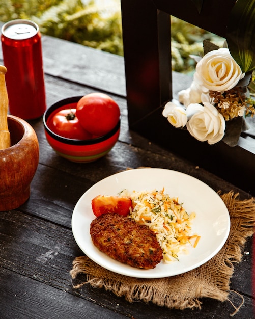 Rice cooked with herbs and carrots and meat cutlet