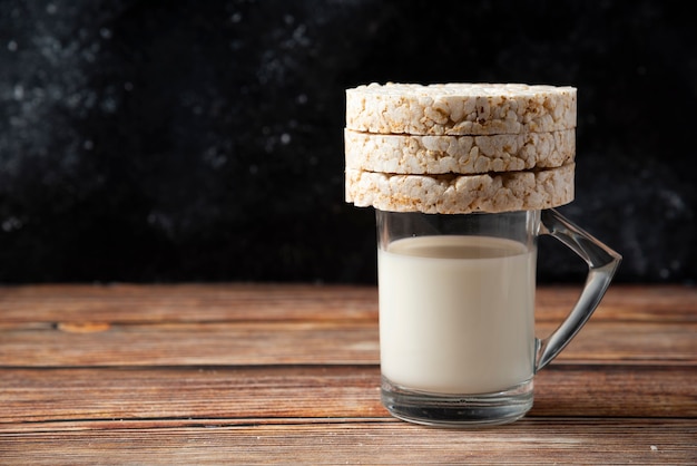 Foto gratuita cracker di riso e bicchiere di latte sulla tavola di legno.