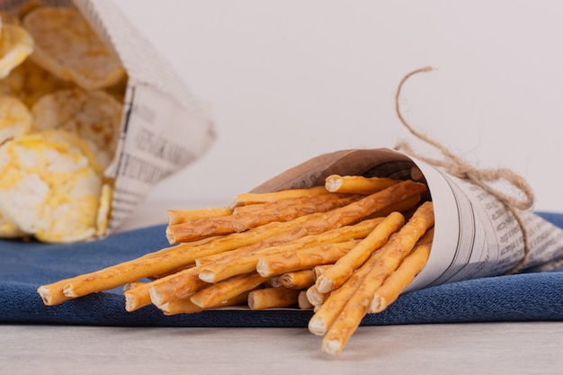 Rice crackers and pretzels on blue tablecloth.