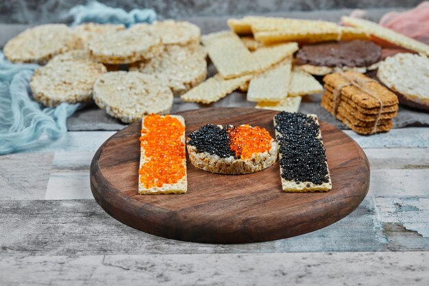 Rice crackers with red and black caviar on a wooden plate. High quality photo