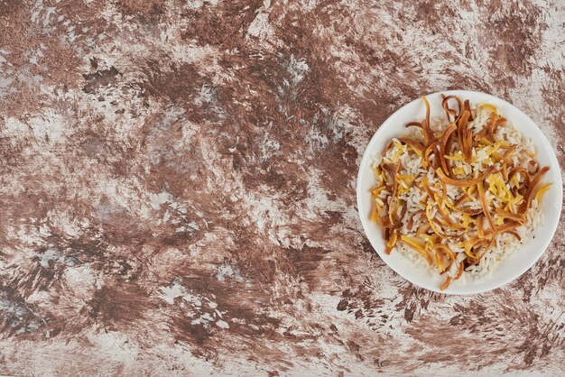 Rice garnish and noodles in a white plate.