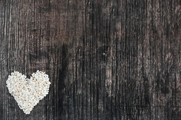 木製の黒い背景で作られた米の心臓の形
