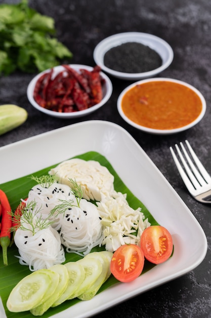 Rice noodles in a banana leaf with beautifully laid vegetables and side dishes. Thai food.