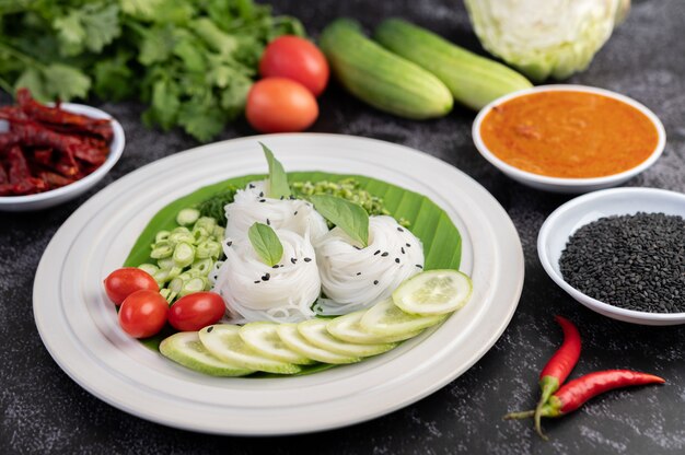 Rice noodles in a banana leaf with beautifully laid vegetables and side dishes. Thai food.