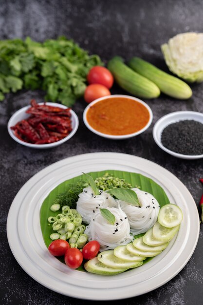 Rice noodles in a banana leaf with beautifully laid vegetables and side dishes. Thai food.