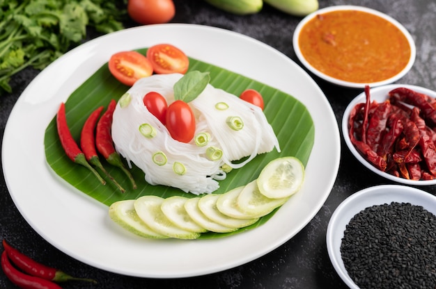 Rice noodles in a banana leaf with beautifully laid vegetables and side dishes. Thai food.