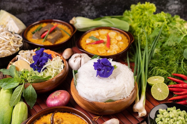 Rice noodles in a bowl of curry paste with chili, cucumber, long bean, lime, garlic and spring onion