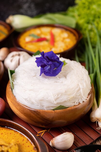 Rice noodles in a bowl of curry paste with chili, cucumber, long bean, lime, garlic and spring onion