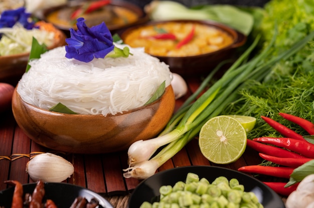 Rice noodles in a bowl of curry paste with chili, cucumber, long bean, lime, garlic and spring onion