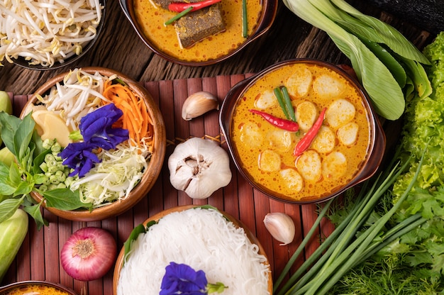 Rice noodles in a bowl of curry paste with chili, cucumber, long bean, lime, garlic and spring onion