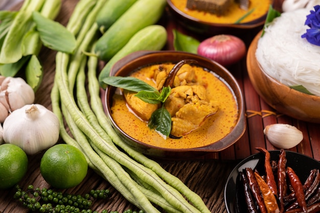 Free photo rice noodles in a bowl of curry paste with chili, cucumber, long bean, lime, garlic and spring onion