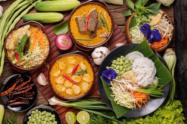 Rice noodles in a bowl of curry paste with chili, cucumber, long bean, lime, garlic and spring onion