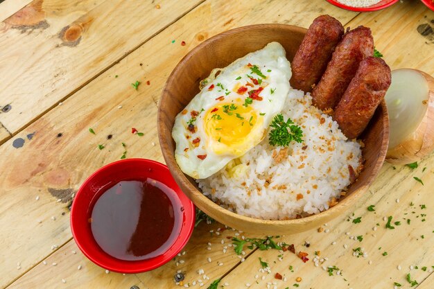 Rice, omelet and sausages with seasonings served in a bowl and souse nearby