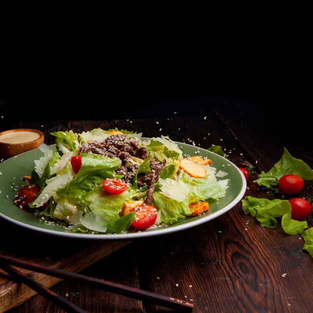 Rice pouring on delicious salad meal in a plate with chopsticks on a wooden and black background side view. space for text