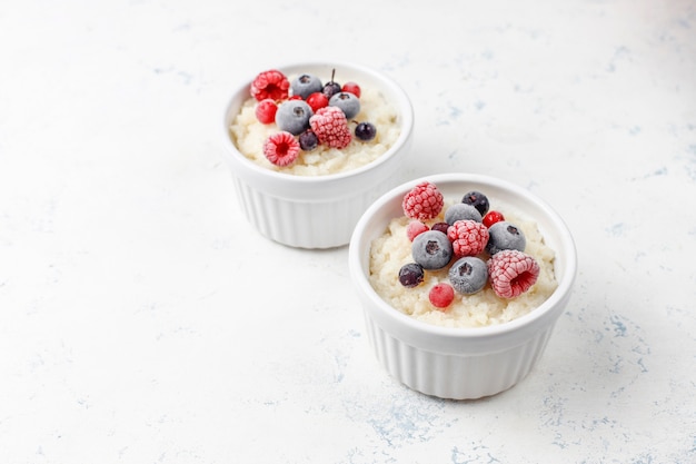 Free photo rice pudding with frozen blueberries and raspberries in white bowl