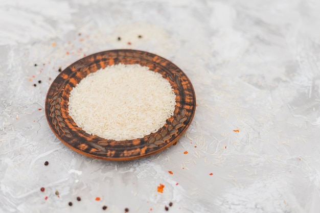 Rice of small antique plate with rice grains on grey concrete backdrop