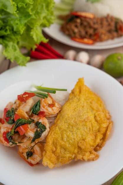 Rice topped with shrimp and omelet on a white plate.