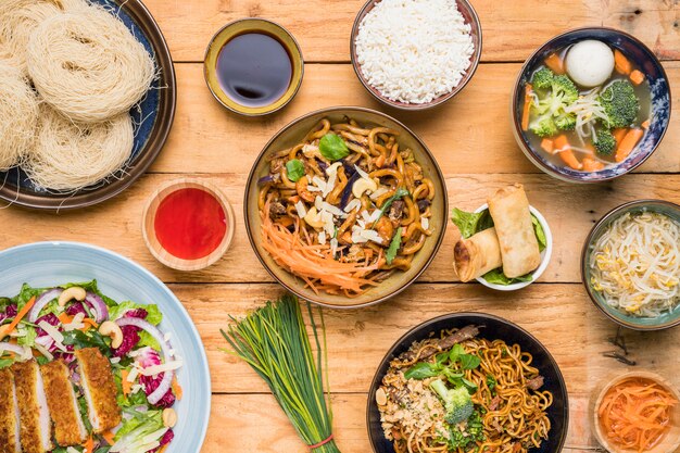 Rice; udon noodles; spring rolls; chives; sprout beans; fish ball soup and salad on table