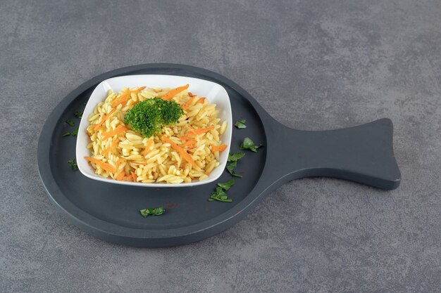 Rice with carrot slices and broccoli on white plate. High quality photo