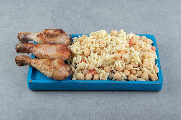 Rice with chickpeas and chicken chicken legs on blue plate.