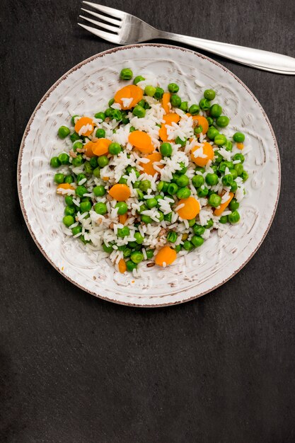 Rice with green beans and carrot on plate near fork 
