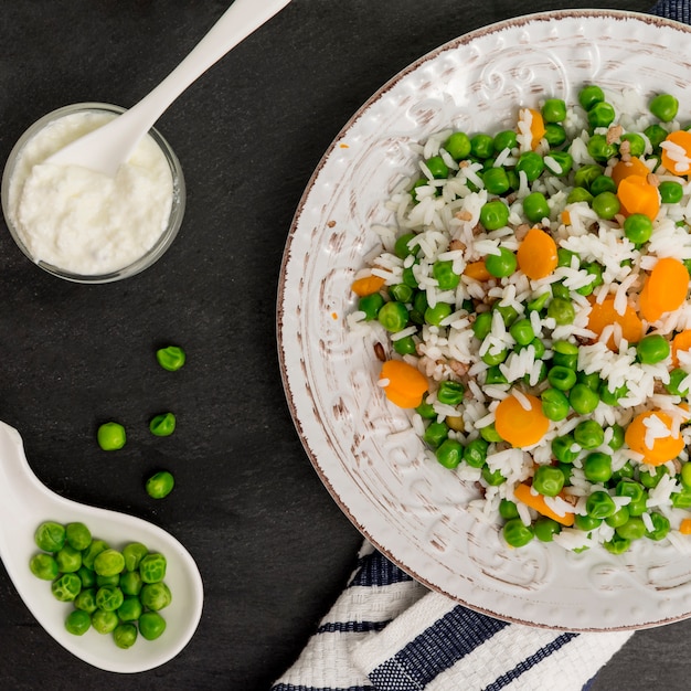 Rice with green beans and carrot on plate near sauce in bowl