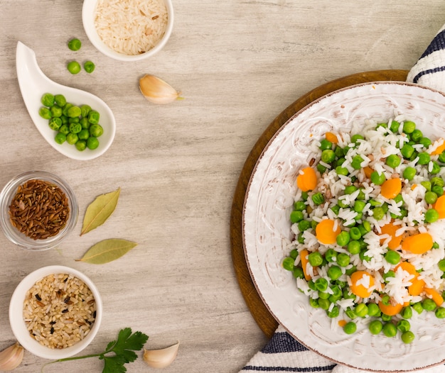 Rice with green beans and carrot on plate with bowls 