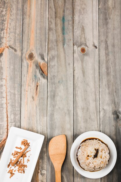 Rice with soya sauce and cinnamon on white tray with spatula on wooden table