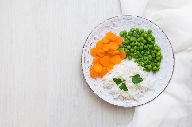 Free photo rice with vegetables and green parsley on plate with white cloth